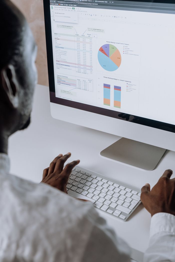 Services Businessman analyzing charts and data on desktop computer in office setting.